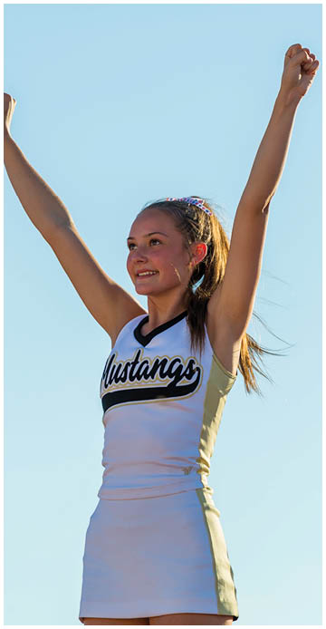 A person with a smiling expression is raising one arm against a clear blue sky. Description generated by AI