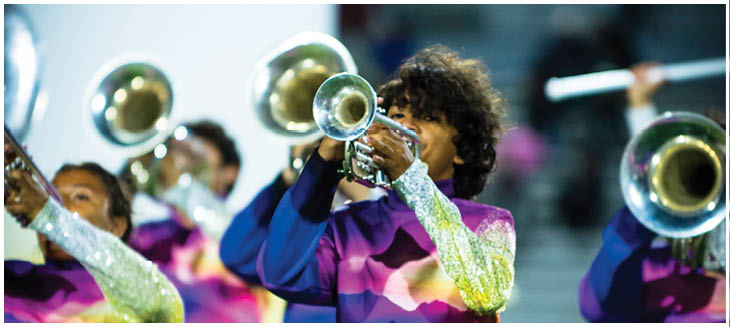 People with curly hair are playing brass instruments in a band setting. Description generated by AI