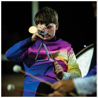 A person wearing a colorful, shiny uniform is playing a triangle instrument while another person in a similar uniform plays a percussion instrument with mallets. Description generated by AI