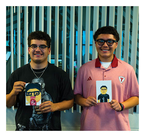 Two people wearing glasses smile while standing in front of vertical blinds, one wearing a black shirt and the other wearing a red collared shirt with a logo. Description generated by AI
