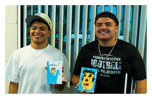 Two people wearing casual clothing and necklaces are smiling while sitting in front of a window with vertical blinds. Description generated by AI