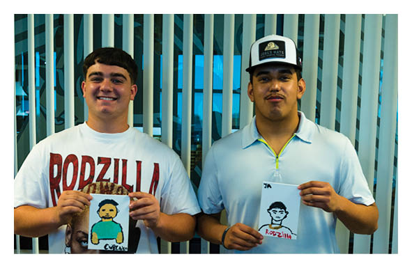 Two adults stand side by side smiling in front of vertical blinds with a modern interior visible behind them. Description generated by AI