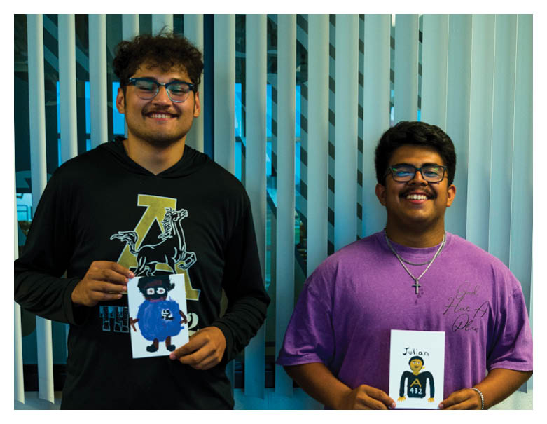 Two adults wearing glasses and smiling stand in front of vertical blinds with a blue light shining through. Description generated by AI
