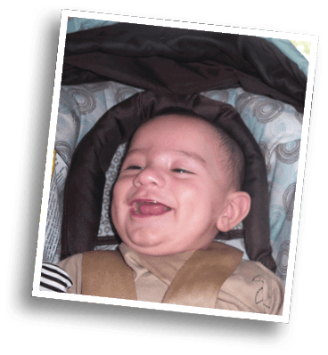 A smiling child wearing a brown outfit is lying on a patterned cushion with circular designs. Description generated by AI