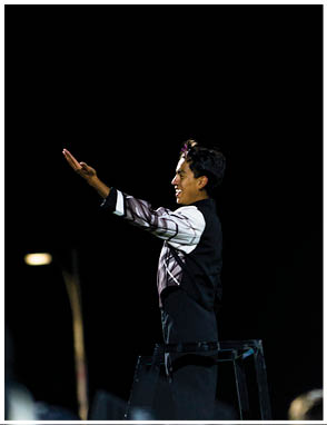A group of people in band uniforms are playing flutes during an outdoor performance at night. Description generated by AI