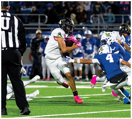 A group of people in sports uniforms are actively playing football on a field with one person running with the ball while others attempt to block or tackle. Description generated by AI