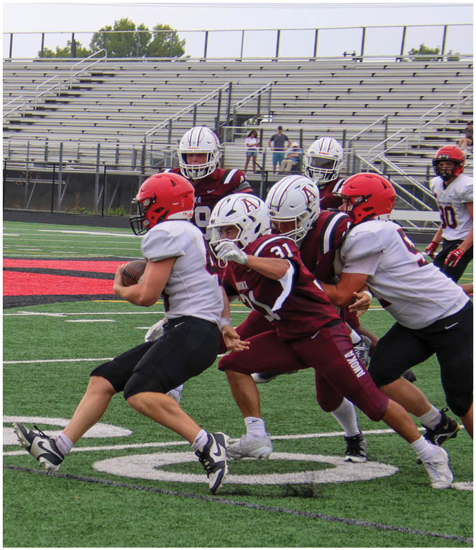 Three football players in blue and white uniforms running on a field. Description generated by AI
