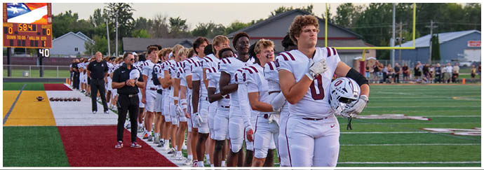 A football game is taking place on a field with players wearing blue and white uniforms. Description generated by AI