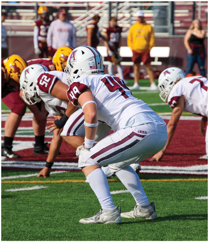 Three football players in blue and white uniforms running on a field. Description generated by AI
