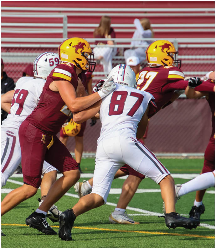 Three football players in blue and white uniforms running on a field. Description generated by AI