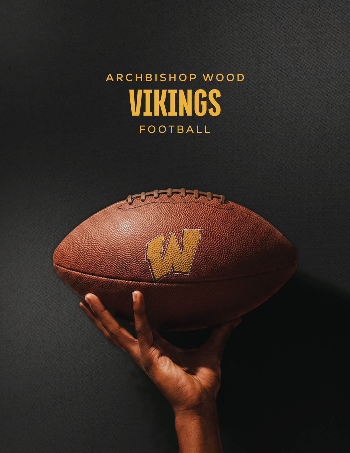 A hand is holding a brown football with a yellow “W" logo against a dark background with the text "Archbishop Wood Vikings Football" above it. Description generated by AI