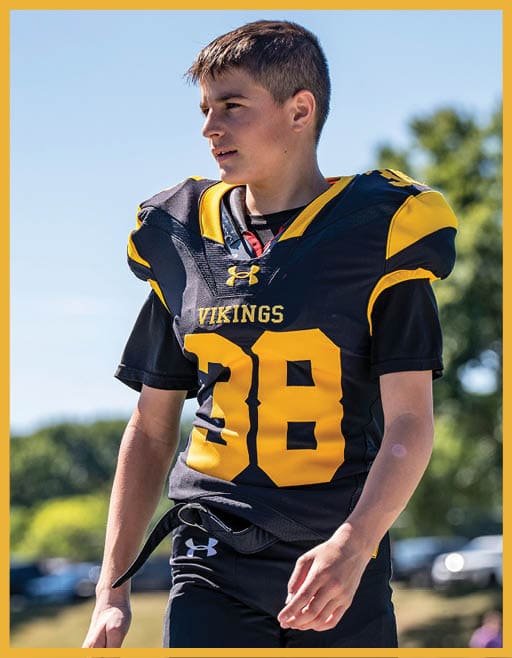 A person wearing a black and yellow Vikings football uniform with the number 38 is standing outdoors on a sunny day. Description generated by AI