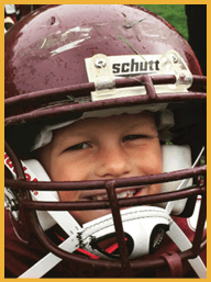 A close-up of a maroon helmet with a small hole and scratches on its surface. Description generated by AI