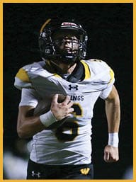 Two people in football uniforms are running on a field at night, with one holding a football and wearing a white jersey with yellow and black accents and the other wearing a dark jersey with the word “TITANS" on it. Description generated by AI