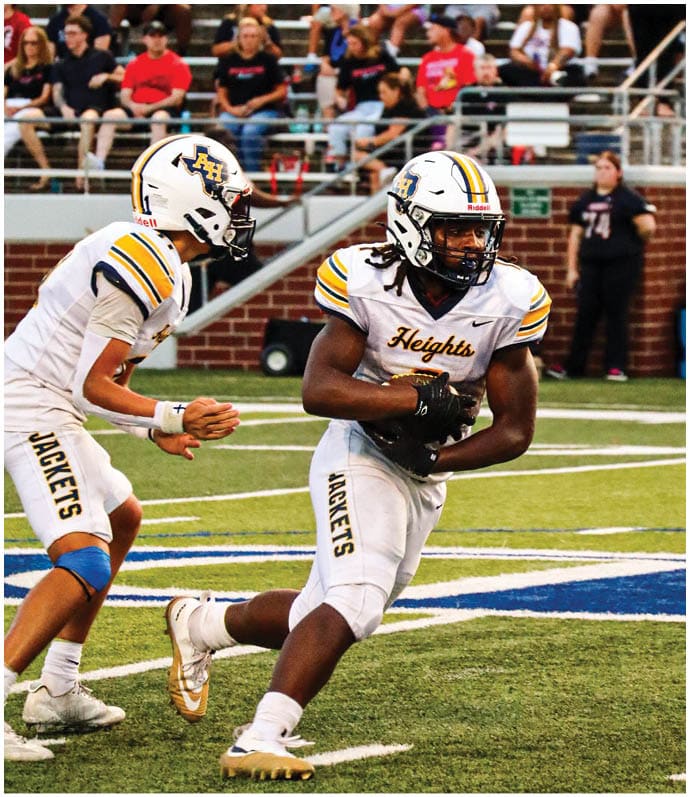 Three football players in blue and white uniforms running on a field. Description generated by AI