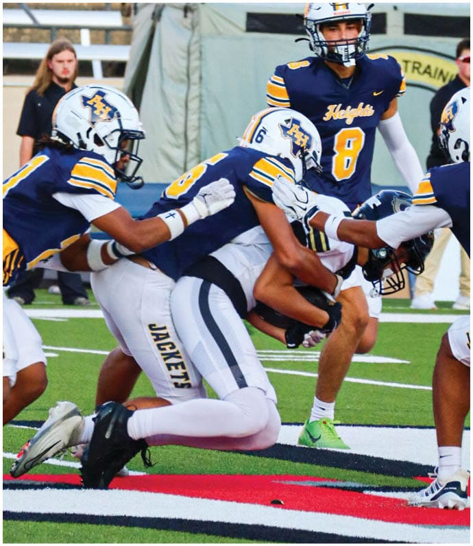 Three football players in blue and white uniforms running on a field. Description generated by AI