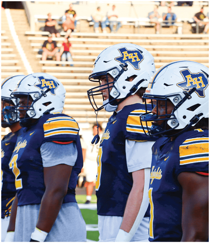 Three football players in blue and white uniforms running on a field. Description generated by AI