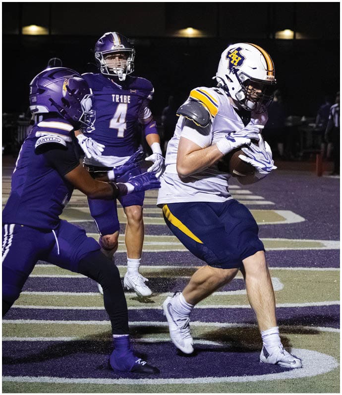 Three football players in blue and white uniforms running on a field. Description generated by AI