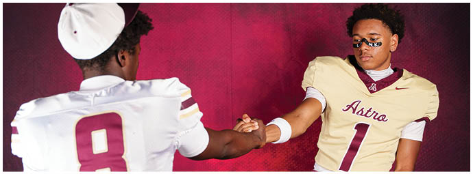 Two people wearing football uniforms with numbers 8 and 1 are clasping hands against a red background. Description generated by AI