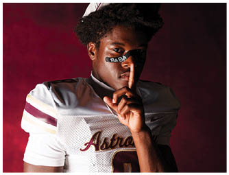 A person wearing a white football uniform and cap with “Astros" on the jersey holds a finger to their lips with "BABY" written on their face against a dark red background. Description generated by AI