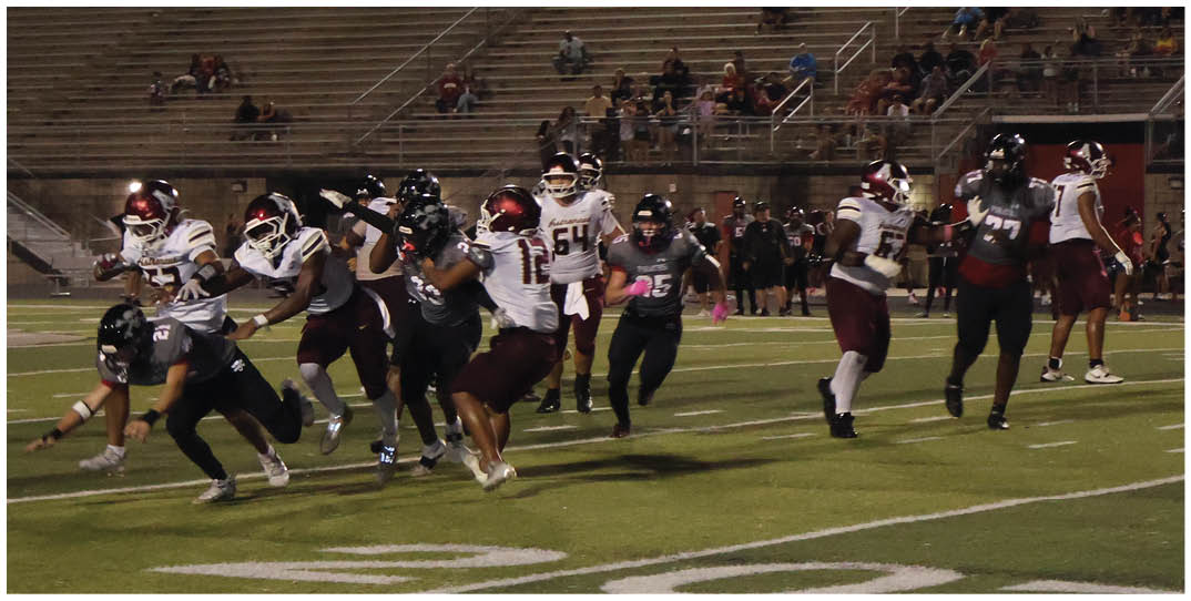 People in football uniforms are actively running and competing on a grassy field during a game. Description generated by AI