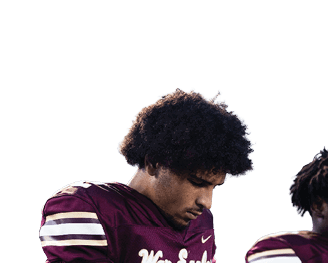 Two people wearing maroon football jerseys with white stripes are standing close together, with one looking downward. Description generated by AI