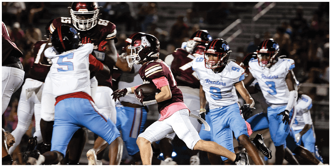 A group of people in football uniforms are actively playing on a field with one person holding the ball and others attempting to block or tackle. Description generated by AI