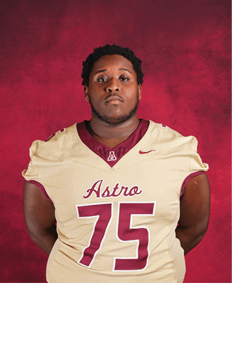 A person wearing a beige and maroon football jersey with the number 75 and the word Astro stands against a red textured background with hands behind their back. Description generated by AI