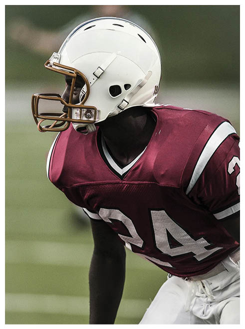 A football player wearing a helmet and jersey with the number 24. Description generated by AI