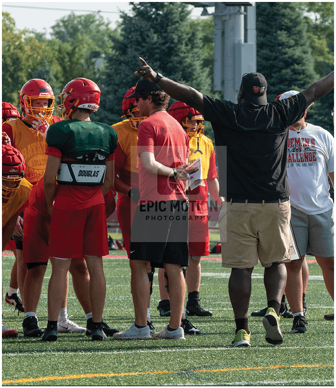 Three football players in blue and white uniforms running on a field. Description generated by AI