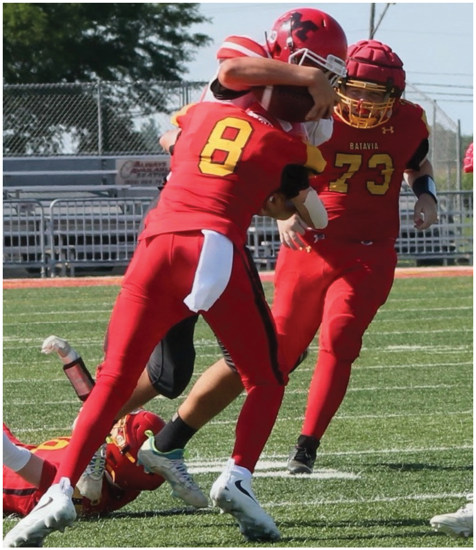 Three football players in blue and white uniforms running on a field. Description generated by AI