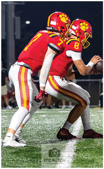 Two football players wearing blue and white uniforms. Description generated by AI