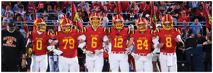 A football game is taking place on a field with players wearing blue and white uniforms. Description generated by AI