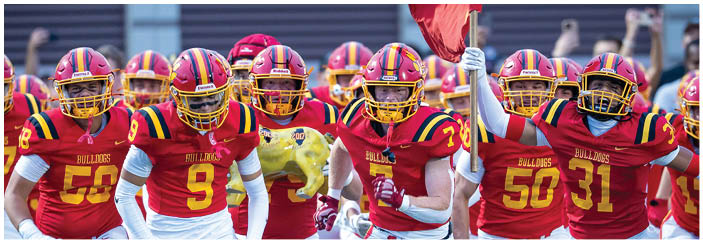A football game is taking place on a field with players wearing blue and white uniforms. Description generated by AI