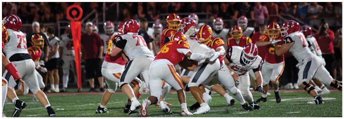 A football game is taking place on a field with players wearing blue and white uniforms. Description generated by AI