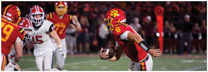 A football game is taking place on a field with players wearing blue and white uniforms. Description generated by AI
