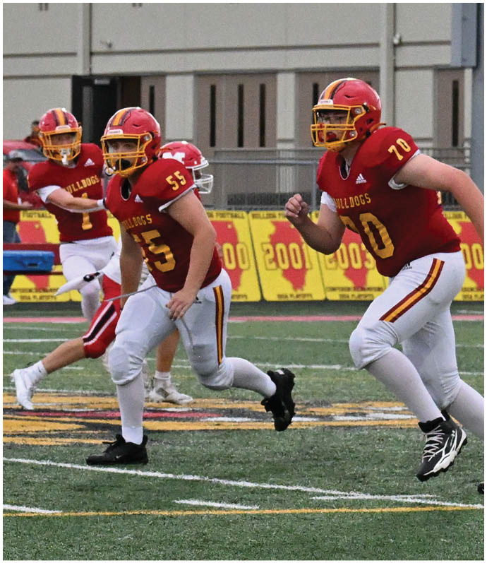 Three football players in blue and white uniforms running on a field. Description generated by AI