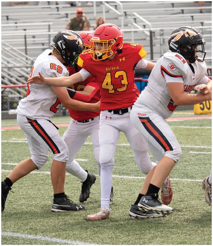 Three football players in blue and white uniforms running on a field. Description generated by AI