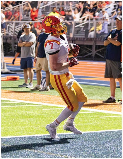A football player wearing a blue and red jersey. Description generated by AI