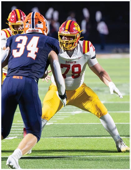 A football player wearing a blue and red jersey. Description generated by AI
