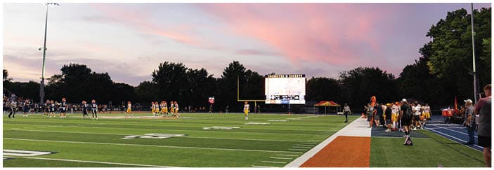 A football game is taking place on a field with players wearing blue and white uniforms. Description generated by AI