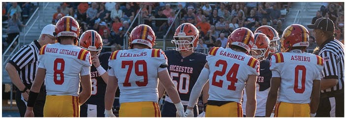 A football game is taking place on a field with players wearing blue and white uniforms. Description generated by AI