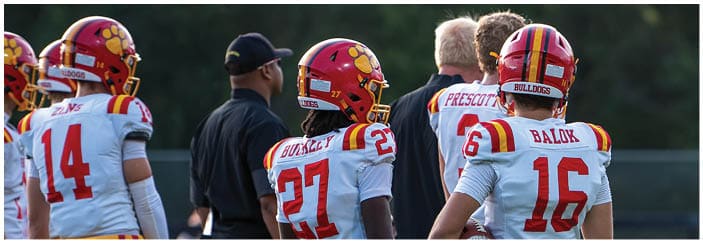 A football game is taking place on a field with players wearing blue and white uniforms. Description generated by AI