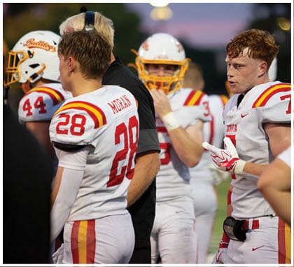 A football game is taking place with a group of men on the field. Description generated by AI