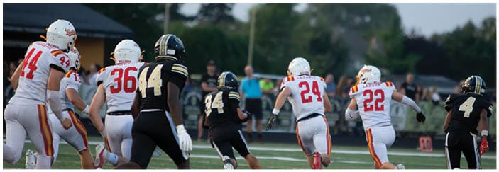 A football game is taking place on a field with players wearing blue and white uniforms. Description generated by AI