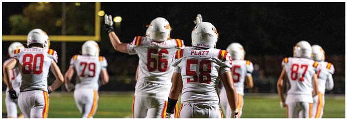 A football game is taking place on a field with players wearing blue and white uniforms. Description generated by AI
