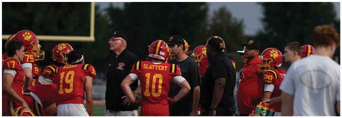 A football game is taking place on a field with players wearing blue and white uniforms. Description generated by AI