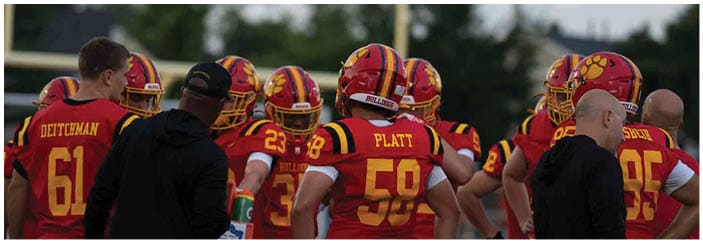 A football game is taking place on a field with players wearing blue and white uniforms. Description generated by AI
