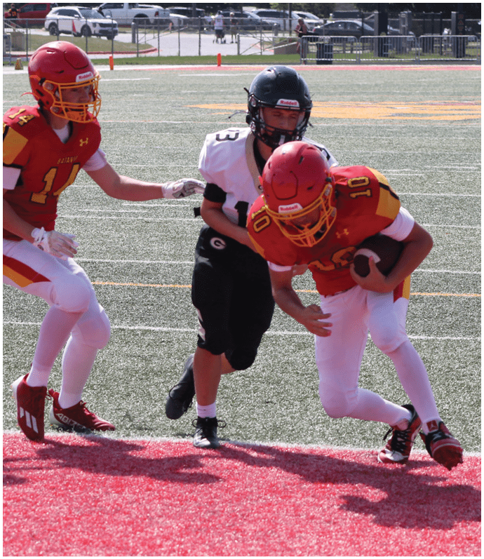 Three football players in blue and white uniforms running on a field. Description generated by AI