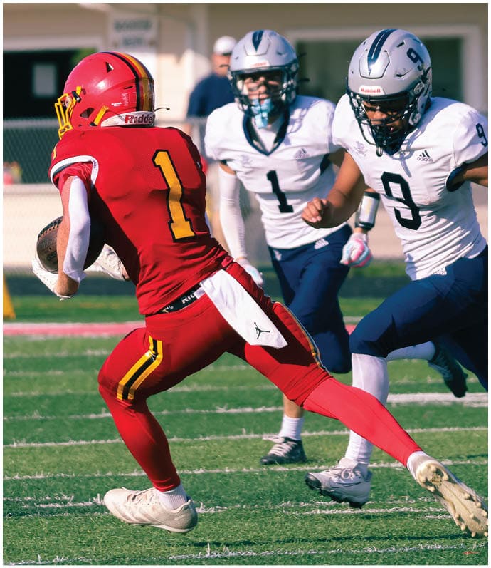 Three football players in blue and white uniforms running on a field. Description generated by AI